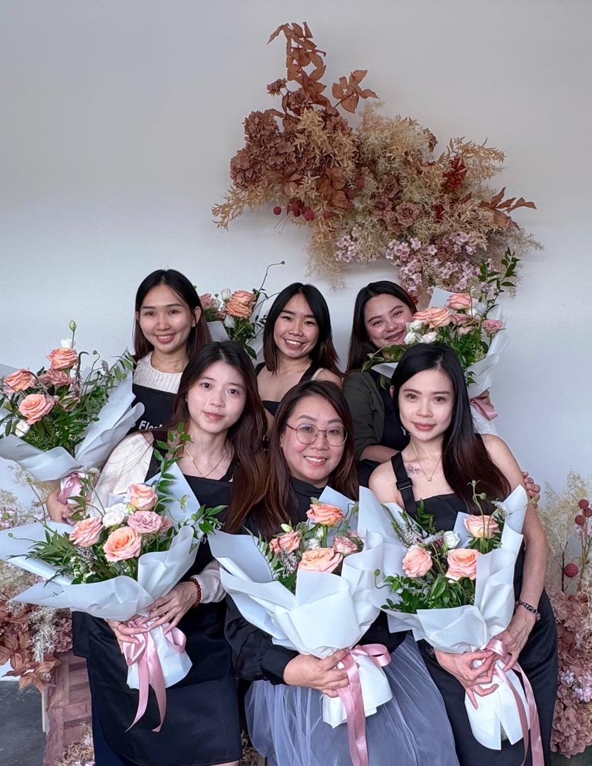 future-florist posing with their instructor while holding their creations