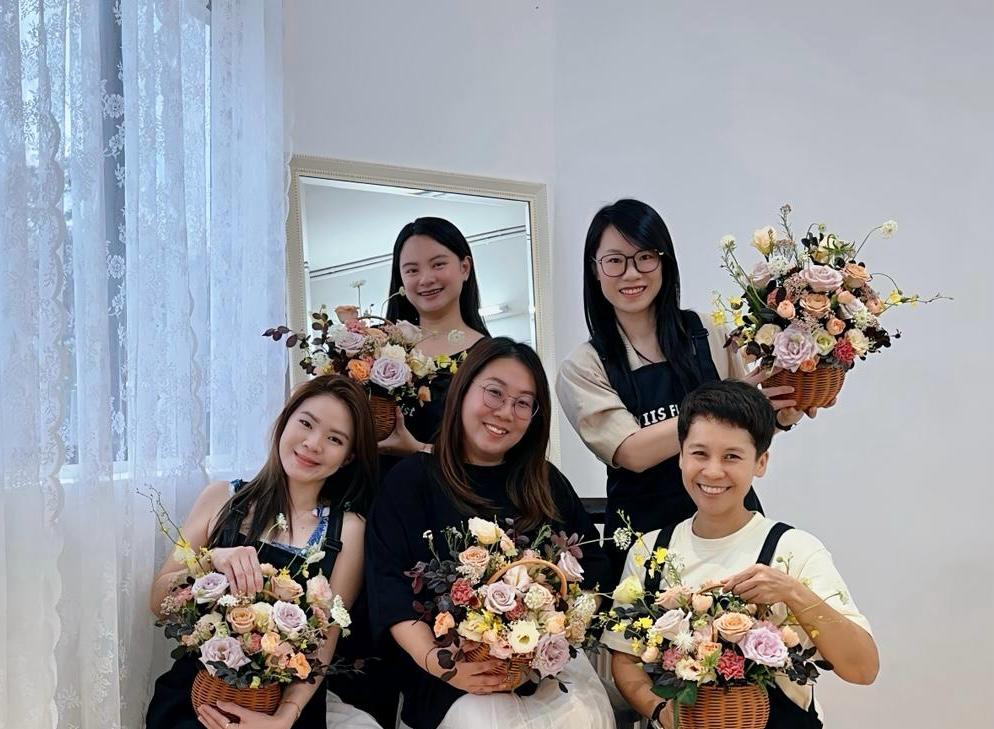 future-florist posing with their instructor while holding their creations
